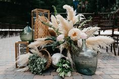 an arrangement of flowers and plants in vases on the ground