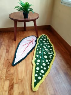 two decorative rugs on the floor next to a table with a potted plant