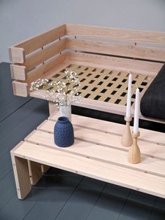 a wooden bench with two vases and candles on the end table next to it