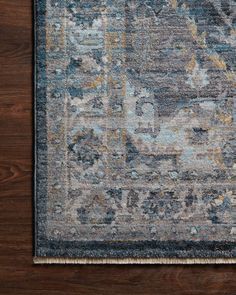 an area rug with blue, yellow and grey colors on the floor in front of a wooden