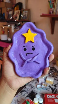 a hand holding a purple cookie with a yellow star on it's face and eyes