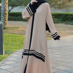 Indulge In The Allure Of Our Beige Striped Modern Abaya, A Perfect Blend Of Sophistication And Fashion-Forward Design. Crafted From Dubai's Renowned Cey Fabric, This Abaya Exudes Elegance And Comfort. Here's Why It's A Must-Have In Your Wardrobe: Key Features: Chic Bell Sleeves: Embrace A Trendy Silhouette With Our Bell Sleeves, Adding A Touch Of Modernity To Your Look. Contrasting Black Strips: The Sleek Black Strips On The Sleeves And Kimono-Style Mandarin Collar Create A Striking Contrast, El Modest Beige Hijab For Eid, Cream Long Sleeve Thobe For Eid, Long Sleeve Cream Thobe For Eid, Beige Long Thobe For Eid, Cream Long Abaya For Eid, Cream Abaya For Eid, Abaya With Hijab, African Kaftan, Modern Abaya