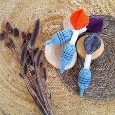 three crocheted hair clips sitting on top of a straw hat next to dried flowers