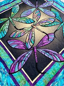 a colorful dragonfly on a black and blue background is featured in this quilted art project