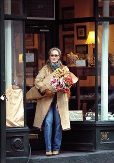 a woman walking out of a store holding flowers