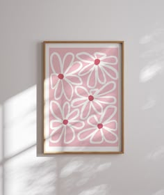 a pink and white flower print hanging on the wall next to a wooden framed object