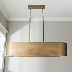 a wooden light fixture hanging from a ceiling in a room with white walls and windows