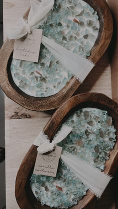 two wooden bowls filled with sea glass on top of a table