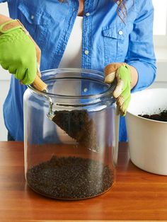 a person in green gloves is cleaning a jar with dirt