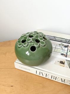 a green vase sitting on top of a book