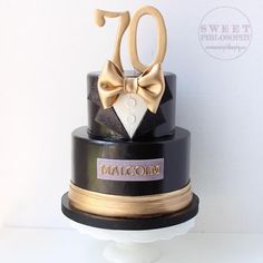 a black and gold cake with the number seventy on it's top tier is adorned with a bow