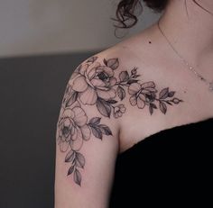 a woman wearing a black dress with flowers on her shoulder and arm tattooing it