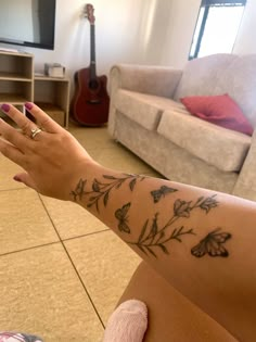 a woman's arm with flowers on it and a guitar in the back ground