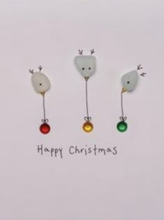 three christmas ornaments hanging from the side of a white card with words happy christmas on it