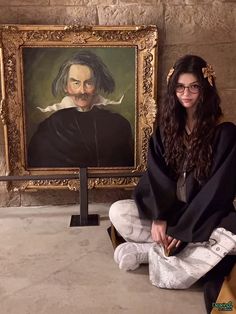 a woman sitting on the ground in front of a painting