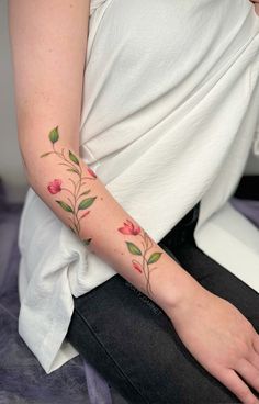 a woman with a flower tattoo on her left arm and right arm is sitting down