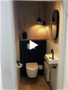 a white toilet sitting in a bathroom next to a sink under a mirror and lights