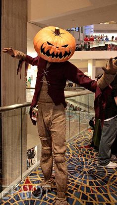 a man dressed up as a scarecrow with a pumpkin on his head