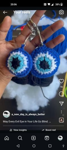 someone is holding up two small crocheted blue and white eyeball keychains