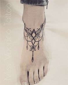 a woman's foot with a black and white tattoo design on her left leg