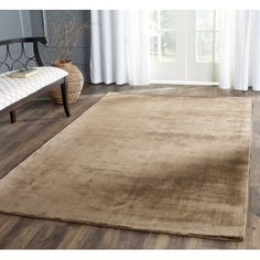 a large brown rug on top of a wooden floor next to a chair and window