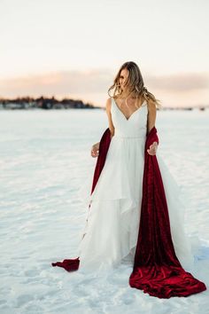 a woman standing in the snow wearing a white and red wedding dress