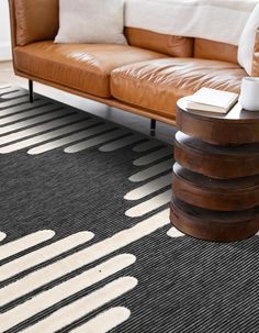 a brown leather couch sitting on top of a wooden floor next to a white and black rug