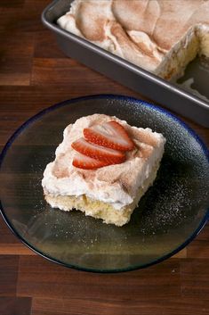 a piece of cake sitting on top of a plate next to a pan filled with strawberries