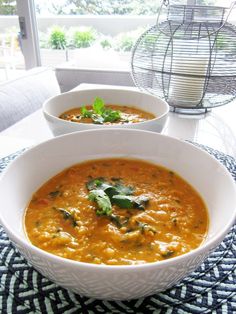 two white bowls filled with soup on top of a table