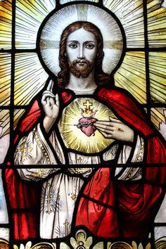 a stained glass window with the image of jesus holding a heart in his right hand