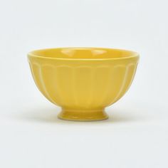 a yellow bowl sitting on top of a white table