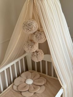 a baby crib with four balls hanging from it's canopy over the bed