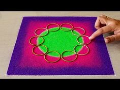 a person is making an art project with colored paper and gold rings on top of it