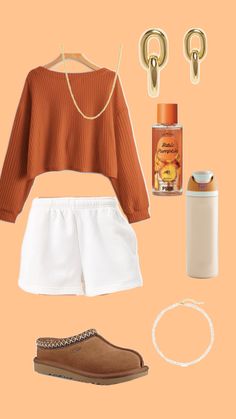 an orange sweater, white shorts and brown shoes are arranged on top of a peach background