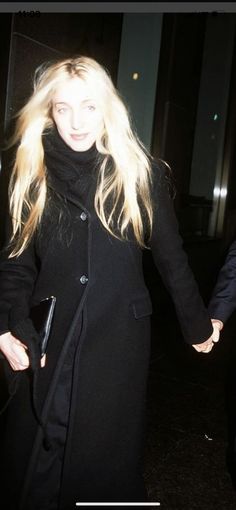 a blonde woman in a black coat holding hands