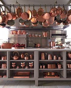 pots and pans are hanging from the ceiling in a large kitchen with stainless steel cabinets