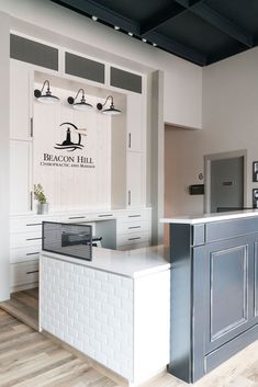 a kitchen with white cabinets and gray counter tops, along with an island in the middle