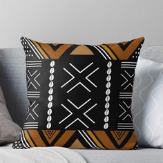 a black and orange throw pillow sitting on top of a couch next to a white pillow