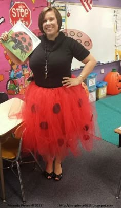 a woman in a ladybug costume poses for the camera while holding a book