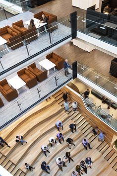 an overhead view of people walking down the stairs in a large building with glass balconies