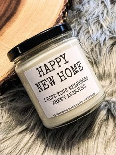 a jar of happy new home candle sitting on top of a fur rug next to a wood slice