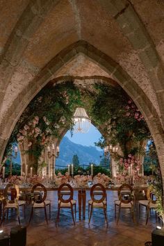 an archway is decorated with flowers and greenery for a formal dining table set up