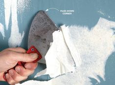 a person is using a knife to cut through some white paint on a wall with the words handyman above it