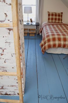 a bed sitting next to a window on top of a blue floor in a bedroom