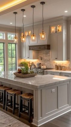 a large kitchen with an island and lots of lights hanging from the ceiling above it