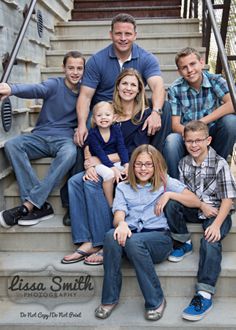 a family sitting on the steps in front of some stairs with their arms around each other