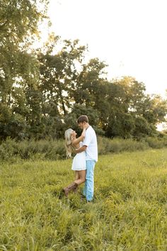 a man and woman holding a dog in a field