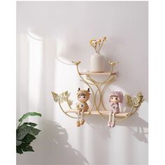 a wall shelf with three figurines on it and a potted plant in the corner