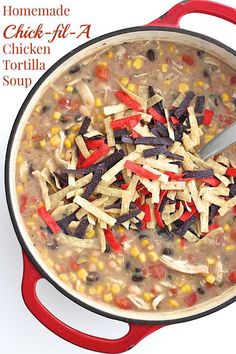 a pot filled with beans and cheese on top of a white counter next to a red spatula