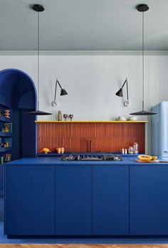 a kitchen with blue cabinets and an arch in the wall, along with wooden flooring